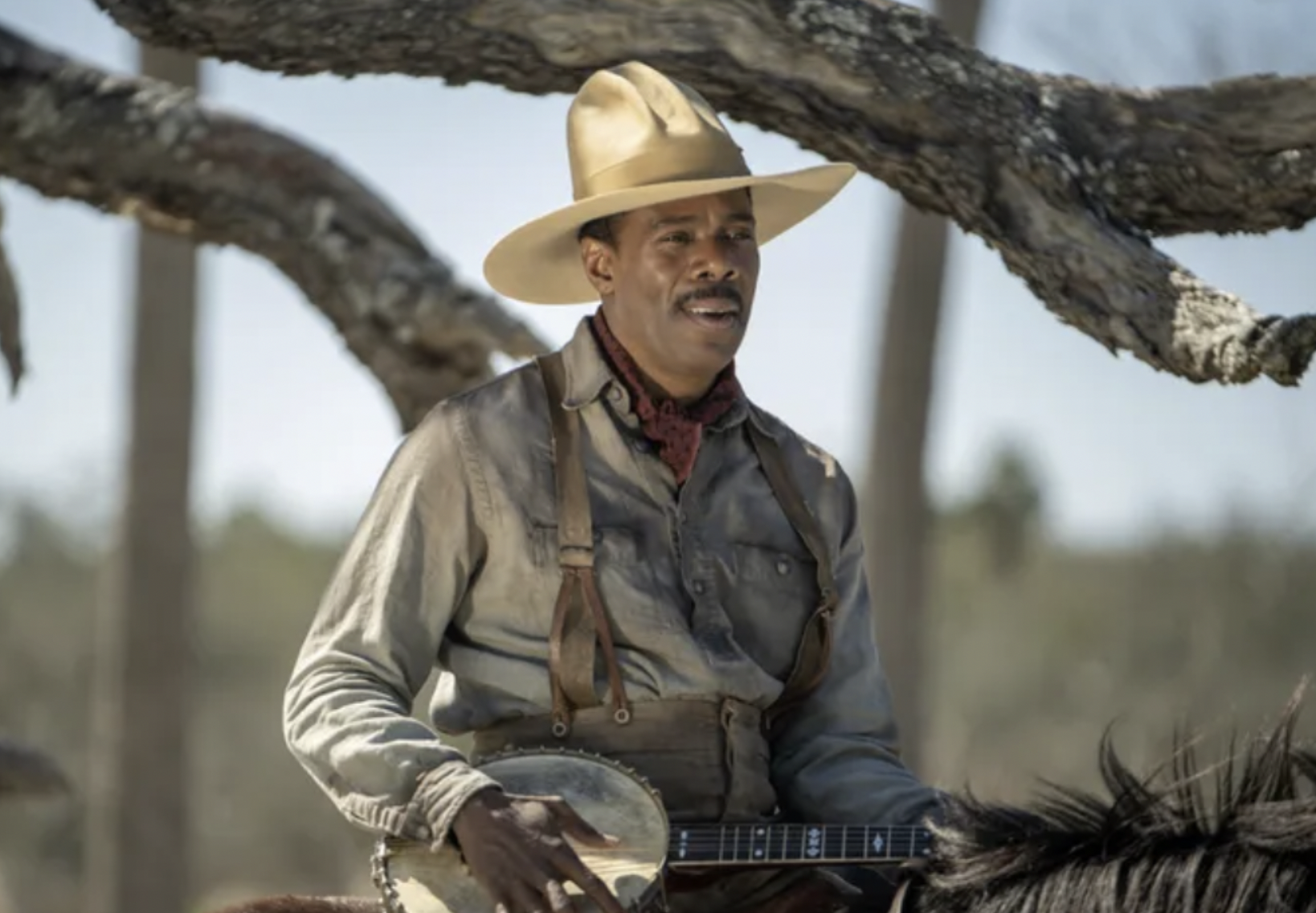 Actor Colman Domingo as Mister in the 2023 adaptation of "The Color Purple." Domingo's Mister sits on a horse, holding a banjo.