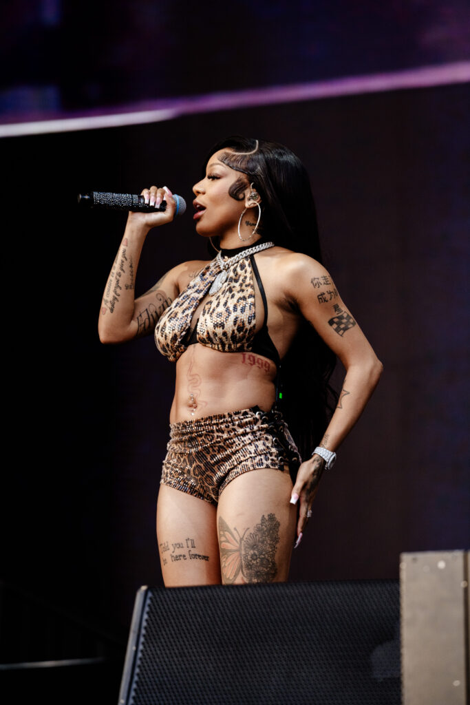 Rapper Glorilla performing onstage while wearing a animal print two-piece in front of a black background.